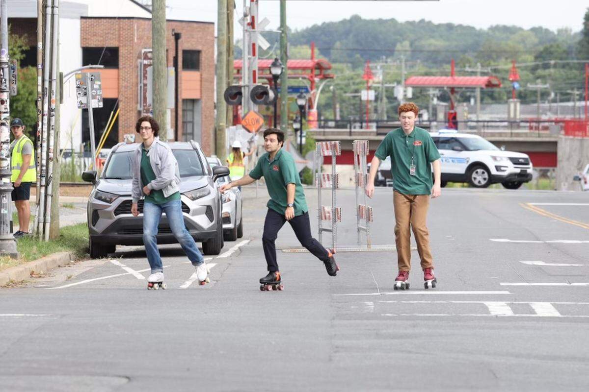 John Higgins, center, and Ben Marshall, right, of “Saturday Night Live”, along with a stunt double representing Martin Herlihy at left, film scenes from “Please Don’t Destroy” in NoDa on July 25. The trio will be in NoDa filming again on August 26.