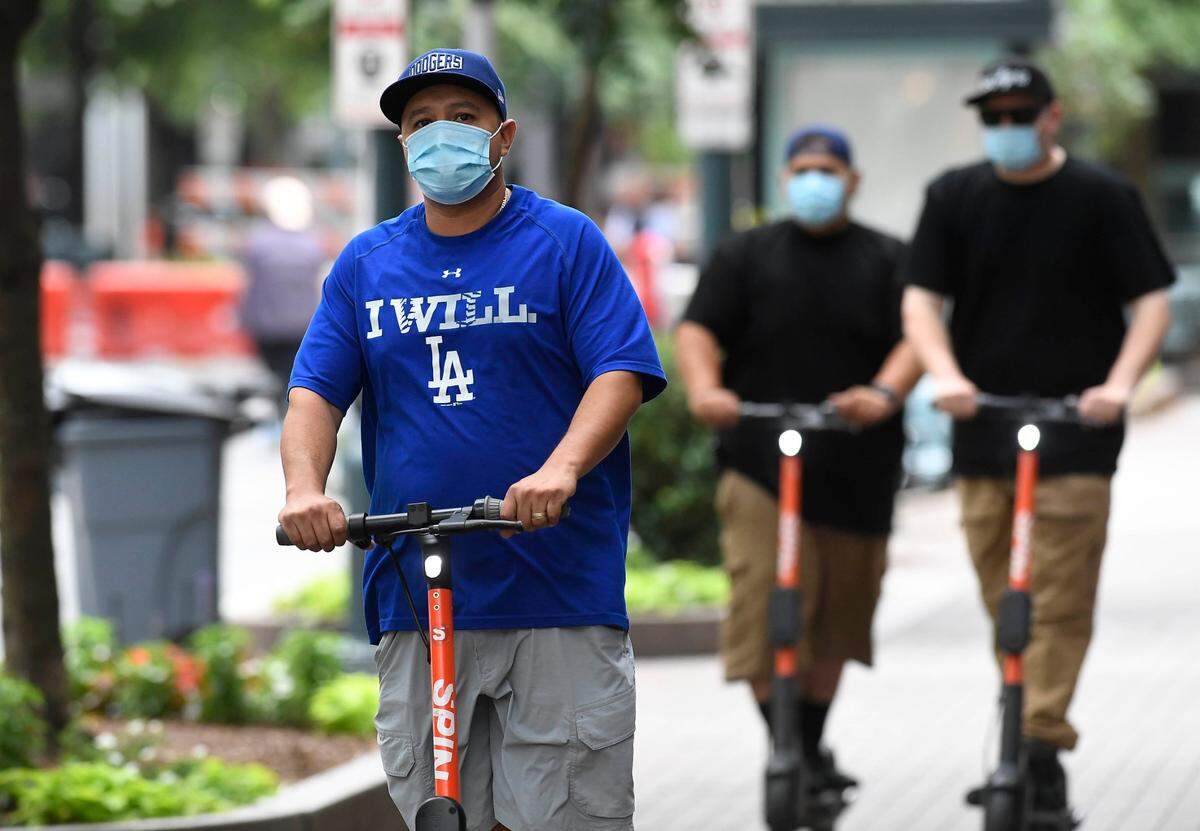 Scooter riders head up the sidewalk along Tryon Street in uptown Charlotte ,while wearing masks, on Wednesday, June 24, 2020. North Carolina Gov. Roy Cooper announced Wednesday the state will remain in Phase Two for another three weeks while making face coverings mandatory in public.