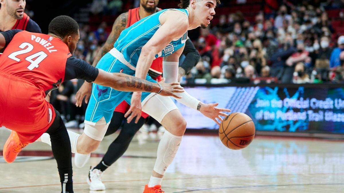 Charlotte Hornets guard LaMelo Ball, right, dribbles past Portland Trail Blazers forward Norman Powell during the first half of an NBA basketball game in Portland, Ore., Friday, Dec. 17, 2021. (AP Photo/Craig Mitchelldyer)