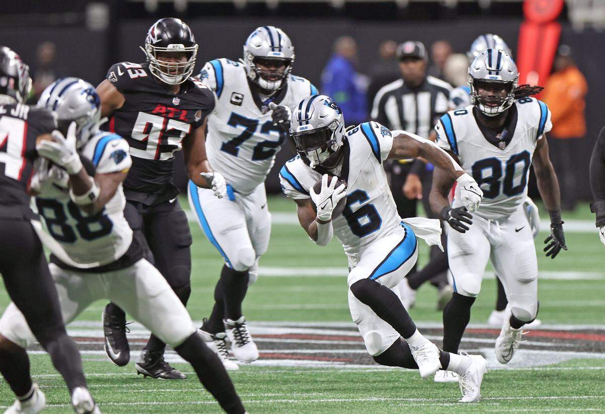 Carolina Panthers running back Miles Sanders, right, follows his blockers for yardage on a run against the Atlanta Falcons during first-quarter action at Mercedes-Benz Stadium in Atlanta, GA on Sunday, September 10, 2023.
