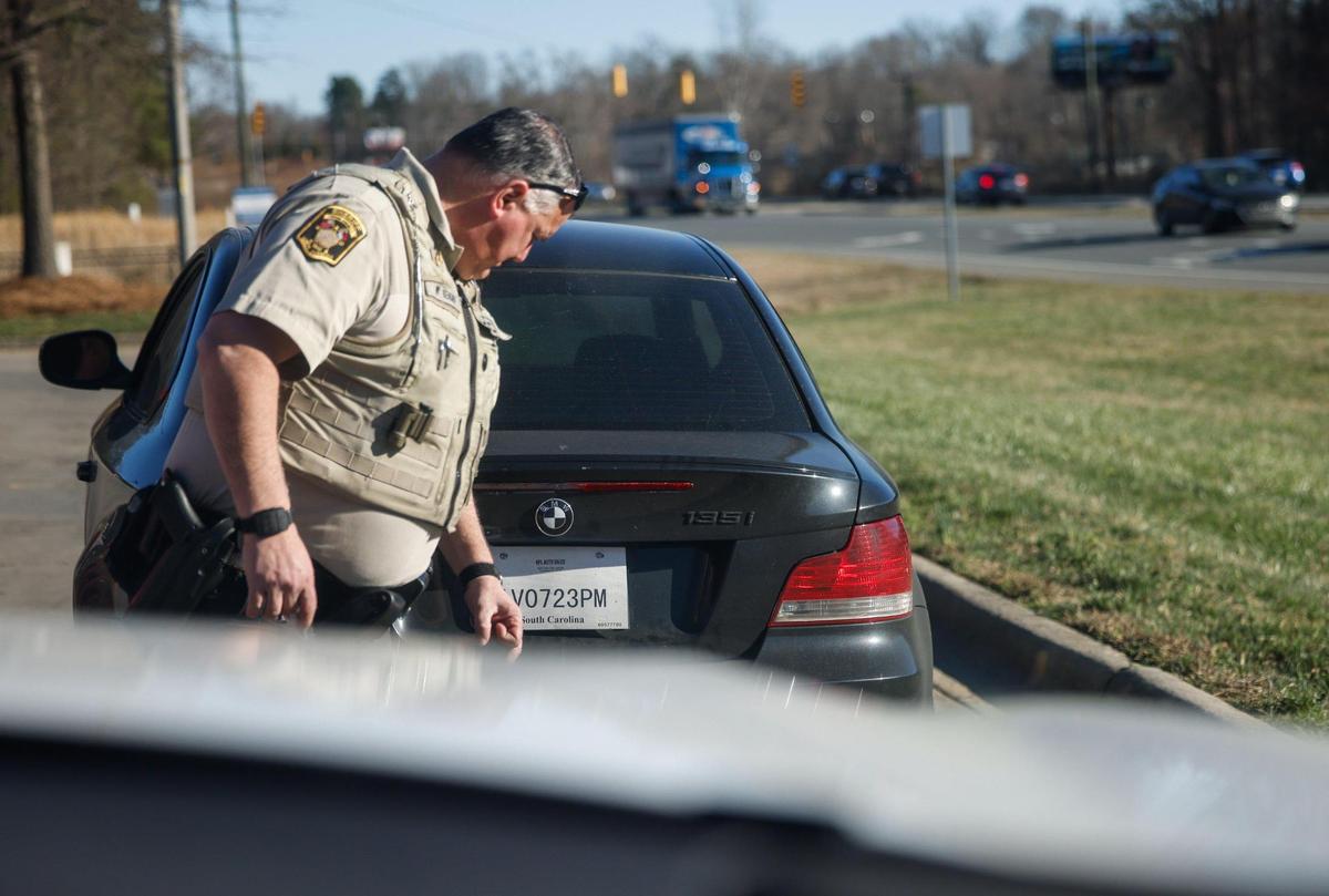 Union County Sheriff Deputy Michael Kenary inspects an expired temporary tag from a car that was pulled over in Indian Trail on Friday.