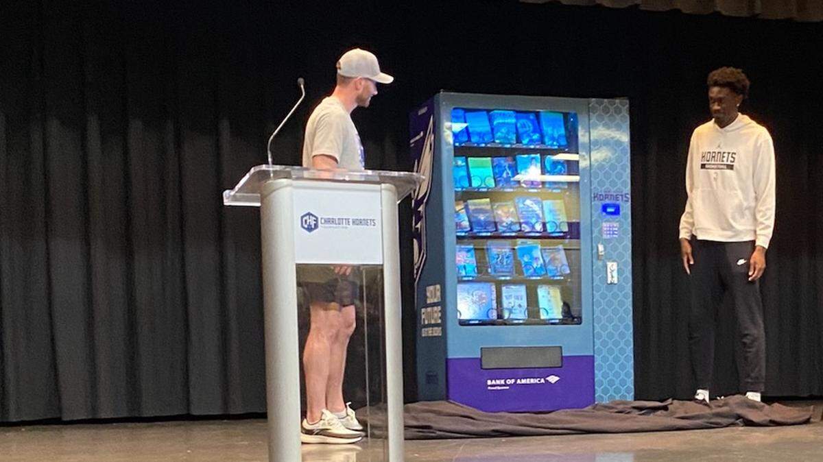 Charlotte Hornets players Gordon Hayward and Mark Williams present a vending machine full of books during an event at Quail Hollow Middle School last week. The goal, school officials say, is to help curb chronic student absences.