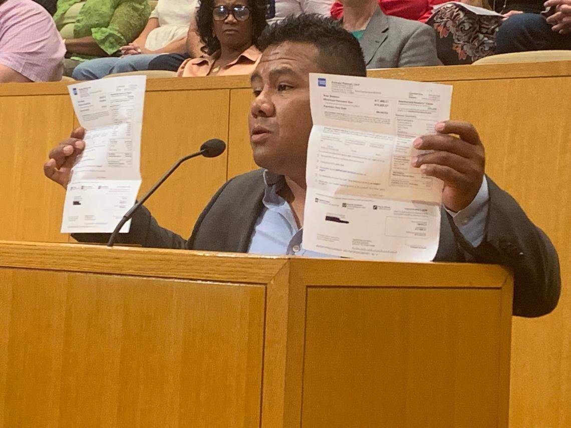 Fruit vendor Jorge Castaneda holds up past due credit card bills that he claims are due to the Central Flea Market closing down.