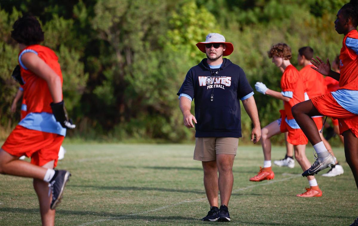 Head Coach Chris Redding watches players as they warm up before practice on Thursday, July 11, 2024. Ballantyne Ridge, a new high school opening this year in south Charlotte, hosted tryouts for its inaugural sports teams including the football team.