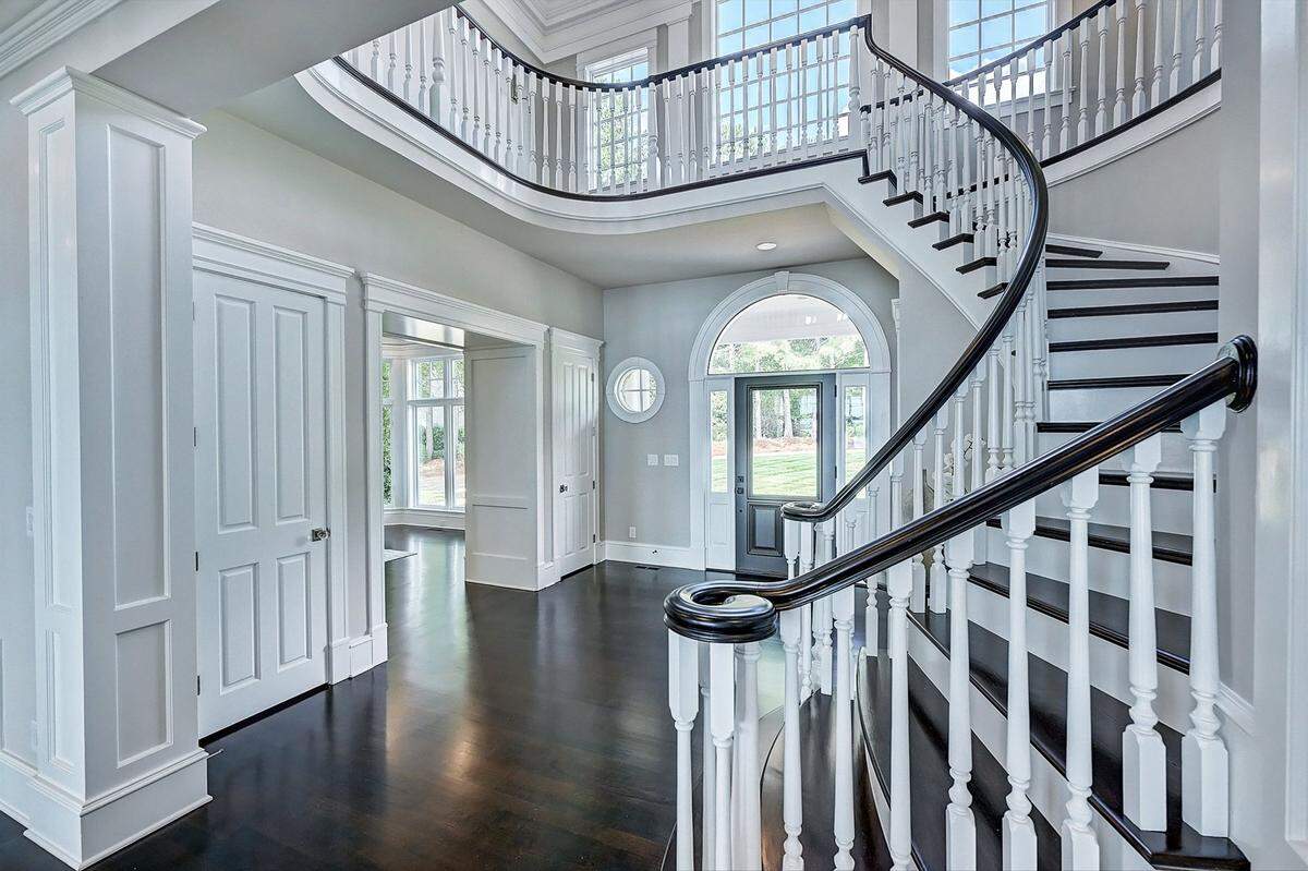 A curved staircase frames the mansion’s two-story foyer.