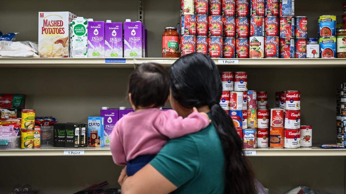 A mother cradles her infant while shopping for groceries at the pantry inside Care Ring on Plymouth Avenue in Charlotte on Thursday, Oct. 31, 2025. Care Ring, a nonprofit organization, is committed to providing healthcare services to the uninsured, underinsured, or those without access to affordable, high-quality healthcare through its Care Ring Clinic and Physicians Reach Out network.