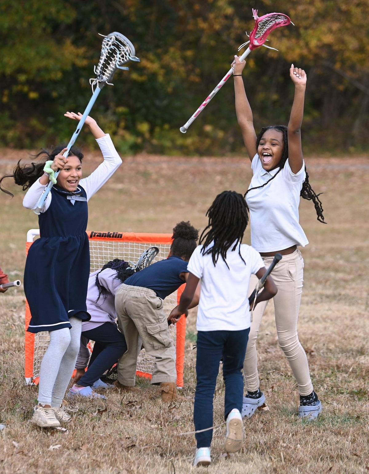 Ainhoa Acuna Cruz, left, and Amaya Montgomery, right, celebrate a goal during a "Play Like Jane" lacrosse clinic hosted by the Greater Enrichment Program at Merry Oaks International Academy last month. Equipment and coaching for the clinic was provided by Jane's Fund, which is an ongoing partnership with GEP.