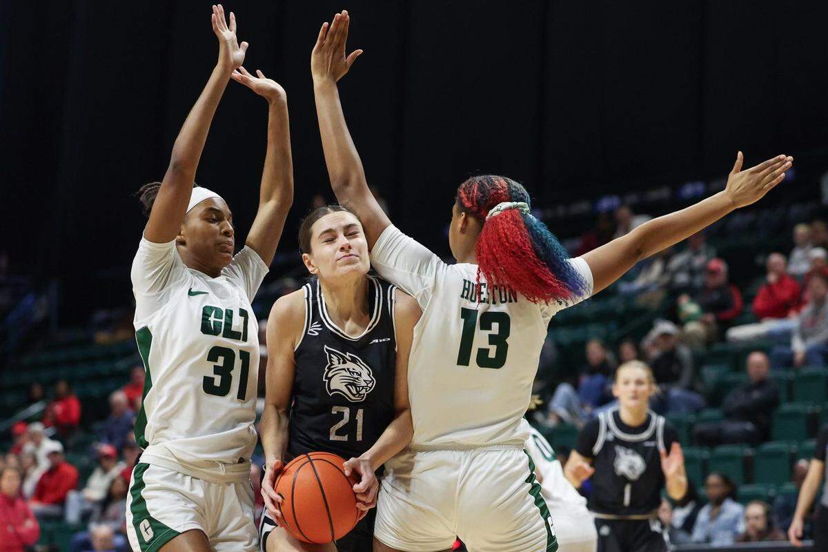 Davidson’s Charlise Dunn (21) is double teamed by UNC-Charlotte’s Keanna Rembert (31) and Tracy Hueston (13) during the game at Halton Arena on Thursday, December 21, 2023.