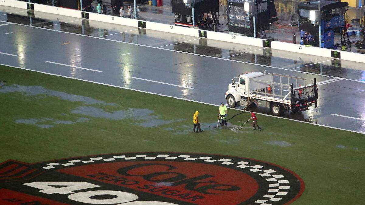 Track workers attempt to clear some of the water off of the infield grass as rain falls before a NASCAR Cup Series auto race at Daytona International Speedway, Saturday, Aug. 27, 2022, in Daytona Beach, Fla. (AP Photo/David Graham)