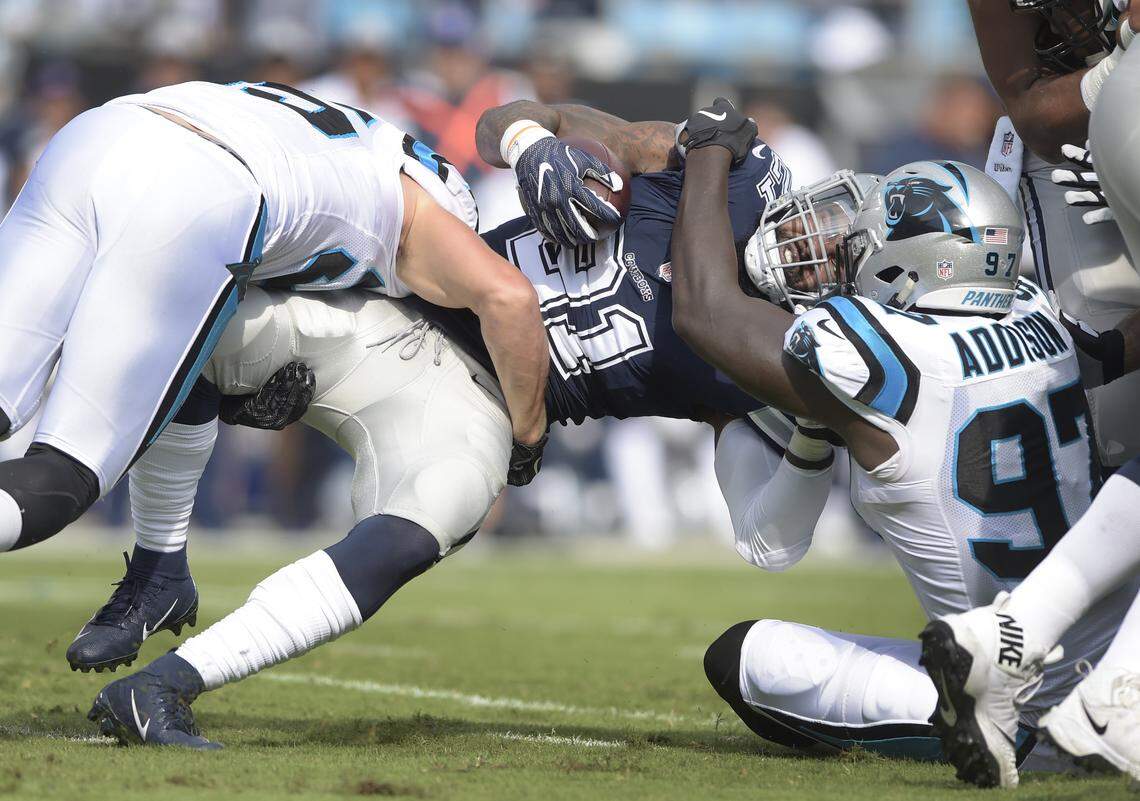 Dallas Cowboys running back Ezekiel Elliott (21) is tackled by Carolina’s Mario Addison (97) Sunday during the season opener for both teams.