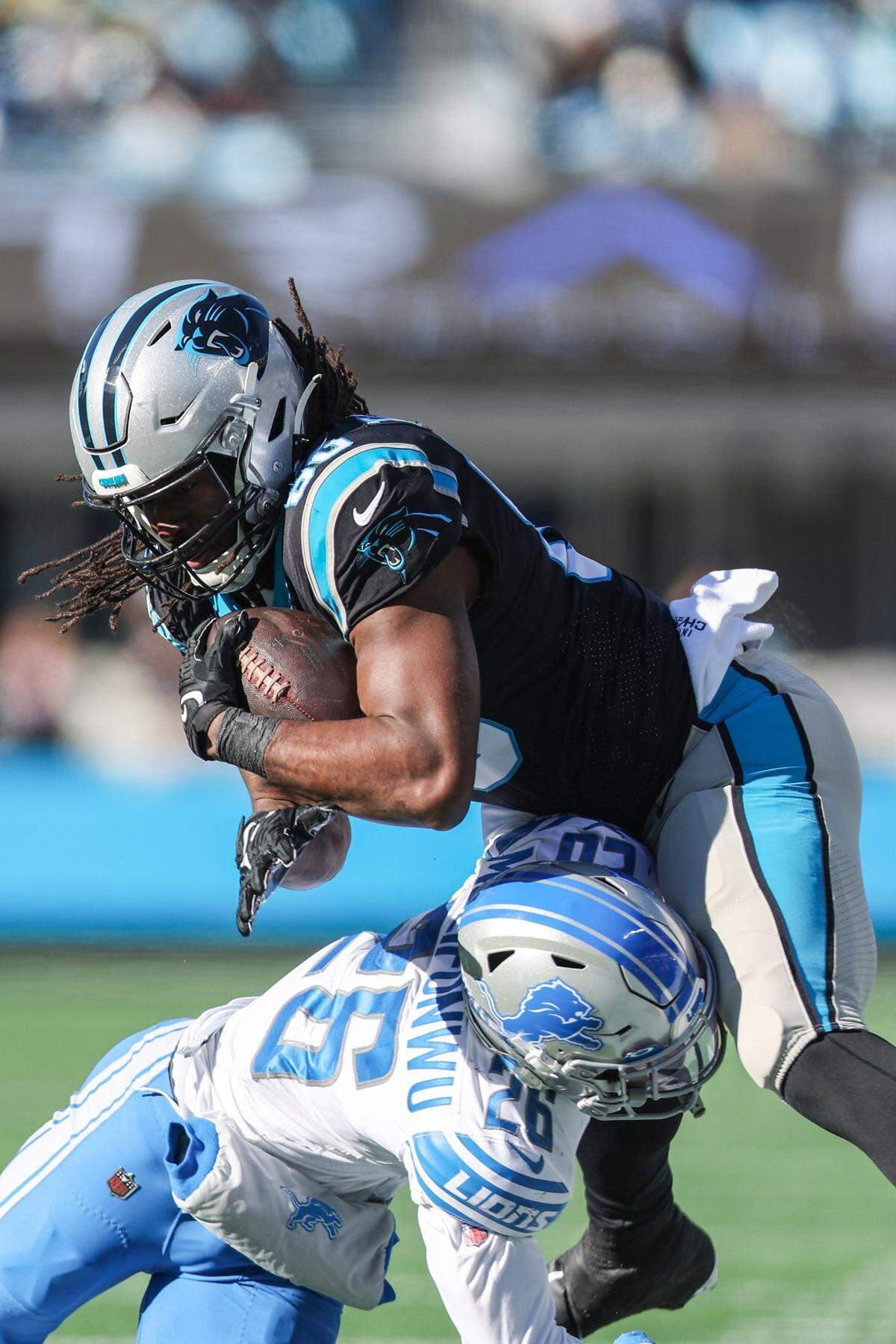 Lions safety Ifeatu Melifonwu, left, tackles Panthers tight end Ian Thomas during the game against the Lions at Bank of America Stadium on Saturday, December 24, 2022.