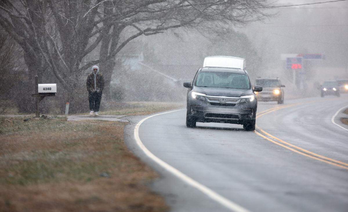 A pedestrian walks through the snowfall along North Carolina Highway 73 on Wednesday, February 19, 2025.