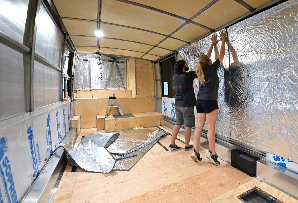 Christian Taylor, left and Avery Hyman, install insulation inside a tour bus. When completed, each bus weighs about 60,000 pounds.