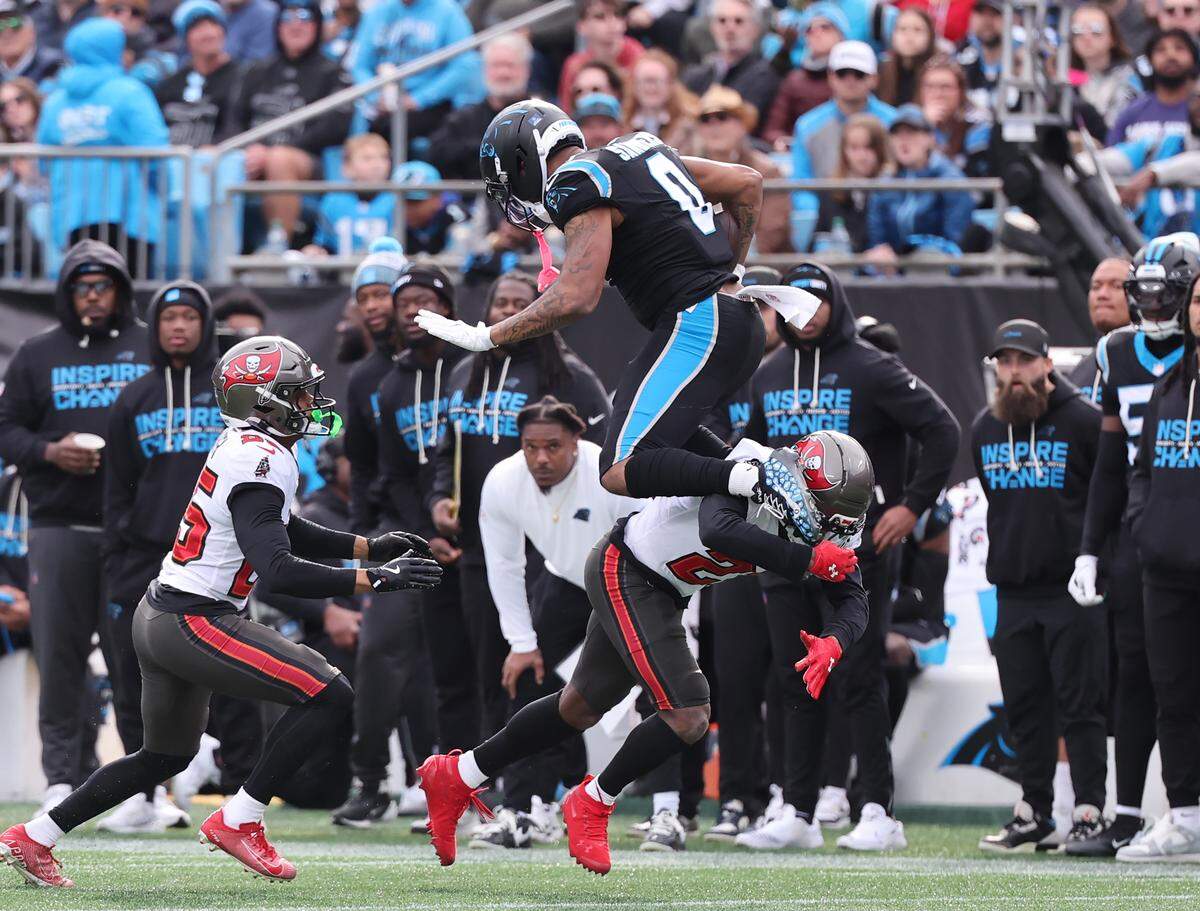 Carolina Panthers Ja'Tavion Sanders leaps over Tampa Bay Buccaneers Benjamin Morrison during a 2025 game at Bank of America Stadium.