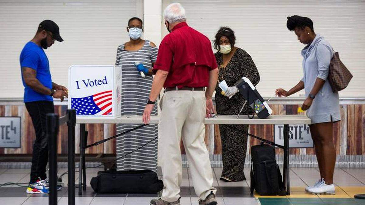 A poll worker stands by as S.C. voters use cotton swabs to press the touch screen during the June primary. In North Carolina, poll workers, many of whom are older and at higher risk for COVID, are expected to be in short supply come November. 