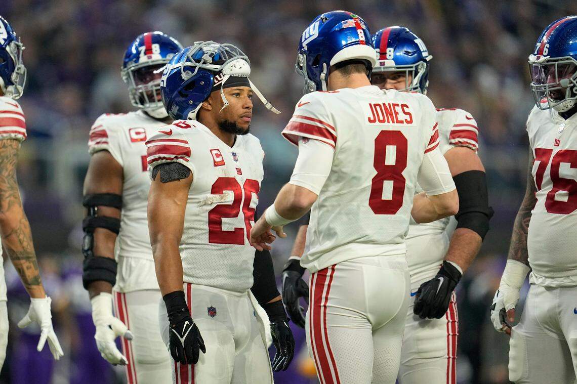 New York Giants running back Saquon Barkley (26), left, and quarterback Daniel Jones (8) talk during the first half of an NFL wild-card football game against the Minnesota Vikings, Sunday, Jan. 15, 2023, in Minneapolis. New York won, 31-24.