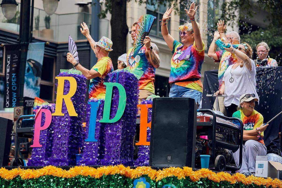 The HugCLT float travels down North Tyron Street as bubbles, fans, and music fill the parade route during the 25th Charlotte Pride Parade in uptown Charlotte on August 17, 2025.