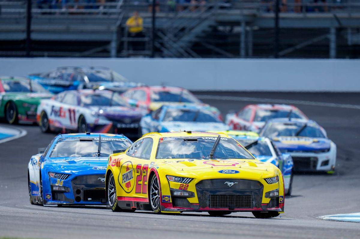 Joey Logano (22) leads a pack of cars through Turn 1 during the running of a NASCAR Cup Series auto race at Indianapolis Motor Speedway, Sunday, July 31, 2022, in Indianapolis. (AP Photo/AJ Mast)