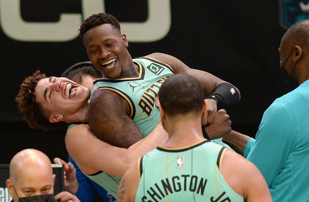 Charlotte Hornets guard Terry Rozier, center, is lifted up in the air by guard LaMelo Ball, left, as they celebrate Rozier’s game-winning basket against the Golden State Warriors.