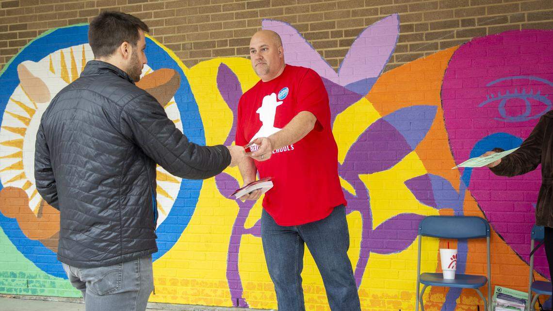 Matt Sears distributes flyers to voters arriving to cast their ballots in the primary election at Lakewood Elementary School on Tuesday, Mar. 3, 2020, in Durham, N.C.