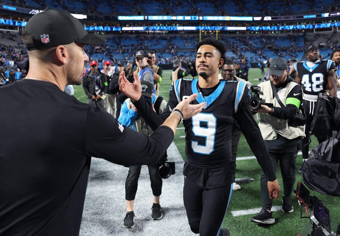 Carolina Panthers head coach Dave Canales, left, reaches out to embrace quarterback Bryce Young, right, following the teams 34-31 loss to the Los Angeles Rams at Bank of America Stadium on Saturday, January 10, 2026. 
