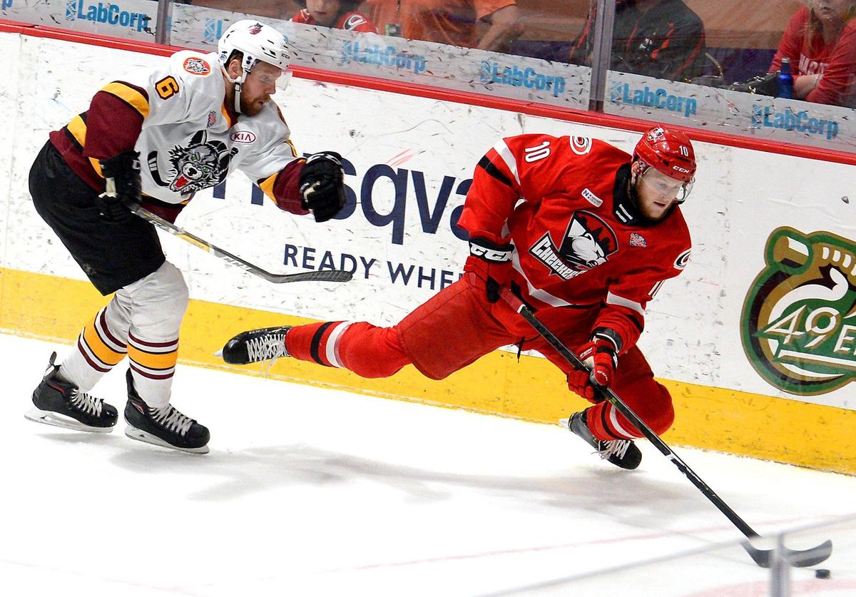 Charlotte Checkers center Steven Lorentz, right, fights to maintain control of the puck while battling Chicago Wolves Griffin Reinhart, during first period action on Sunday.