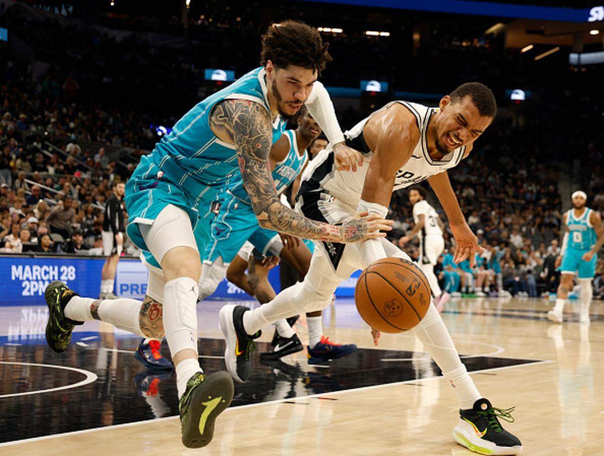 Victor Wembanyama of the San Antonio Spurs battles LaMelo Ball of the Charlotte Hornets for a loose ball in the first half at Frost Bank Center.