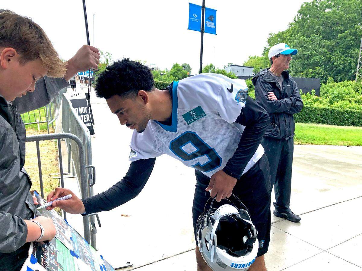 Carolina Panthers quarterback Bryce Young, right, signs an autograph for a fan on Tuesday, May 27, 2025 before OTA practice.