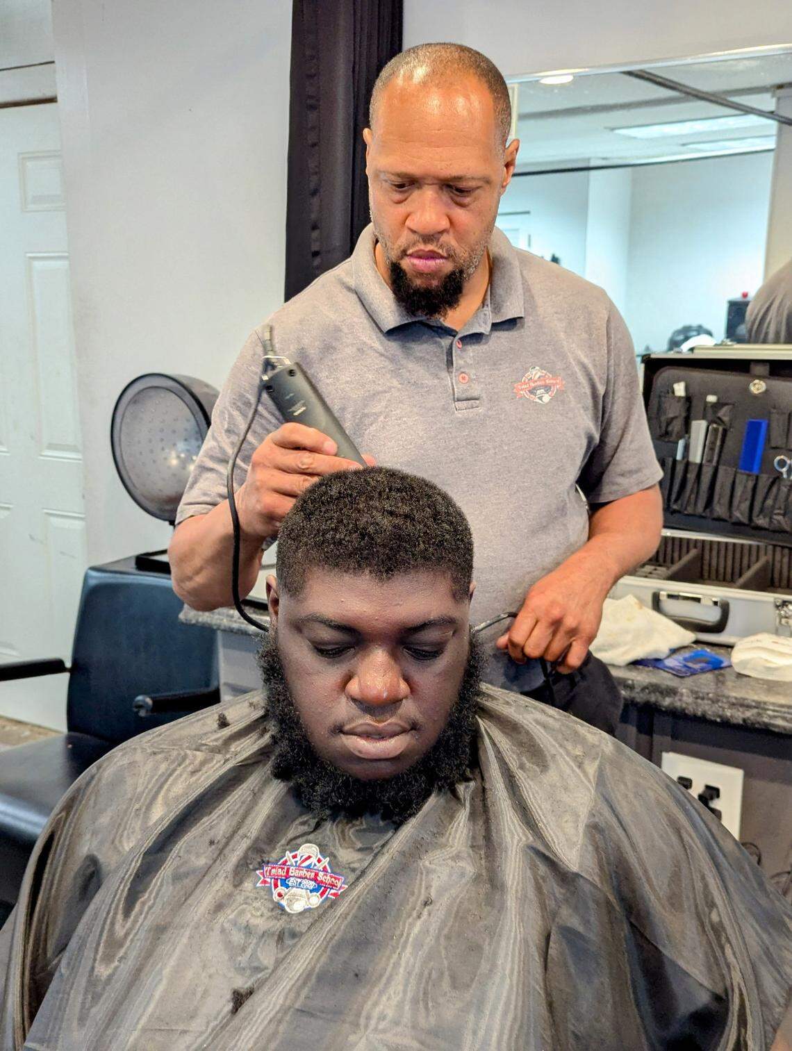 Garrett Snuggs shows a student a trimming technique April 4 at his Triad Barber School on South Rutherford Street in Wadesboro. The city councilman, who also owns Bank Shots Bar & Grill and Tight Cuts barbershop in town, said more bank options would provide residents with more opportunities.