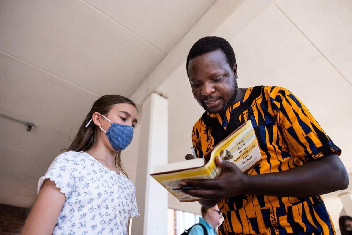 William Kamkwamba, author of “The Boy Who Harnessed the Wind,” autographs a copy of his book for Elizabeth Crimmins, 12, at Randolph Middle School in Charlotte Monday. The book is part of the language arts curriculum for sixth grade students.