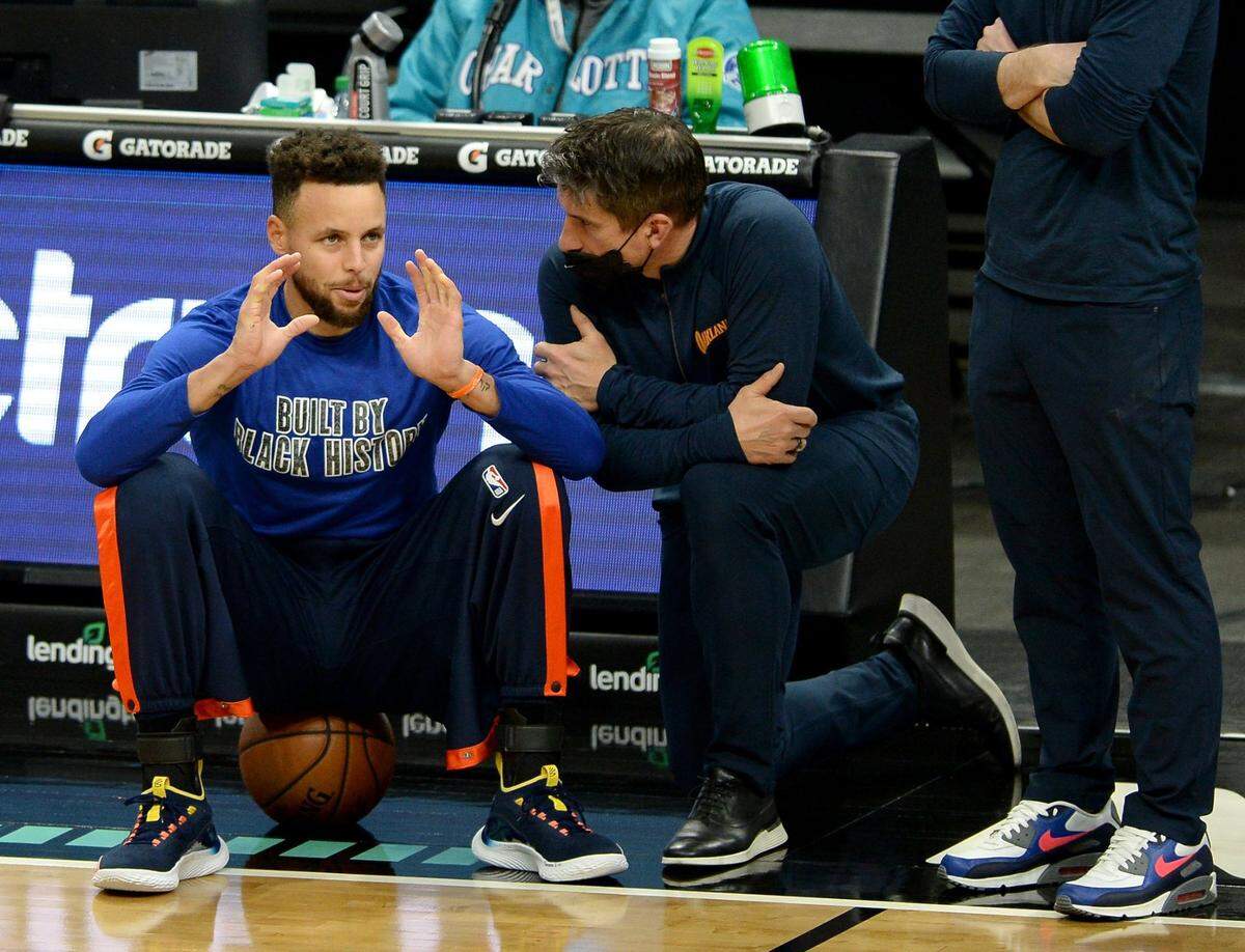 Golden State Warriors guard Steph Curry, left, talks with a member of the teamÕs personnel prior to the teamÕs game against the Charlotte Hornets at Spectrum Center in Charlotte, NC on Saturday, February 20, 2021. Curry became ill prior to tip-off.