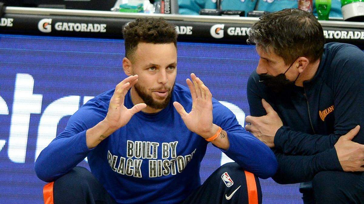 Golden State Warriors guard Steph Curry, left, talks with a member of the team’s personnel prior to the Warriors’ game against the Charlotte Hornets at Spectrum Center in Charlotte, NC on Saturday, February 20, 2021. Curry became ill prior to tip-off and didn’t play in the game, which Charlotte won, 102-100.