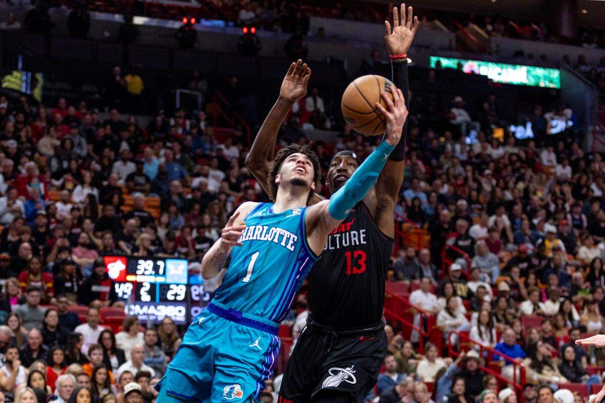 Miami Heat center Bam Adebayo (13) attempts to block Charlotte Hornets point guard LaMelo Ball (1) during the first half of an NBA game at Kaseya Center in Miami, Florida, on Sunday, January 14, 2024.