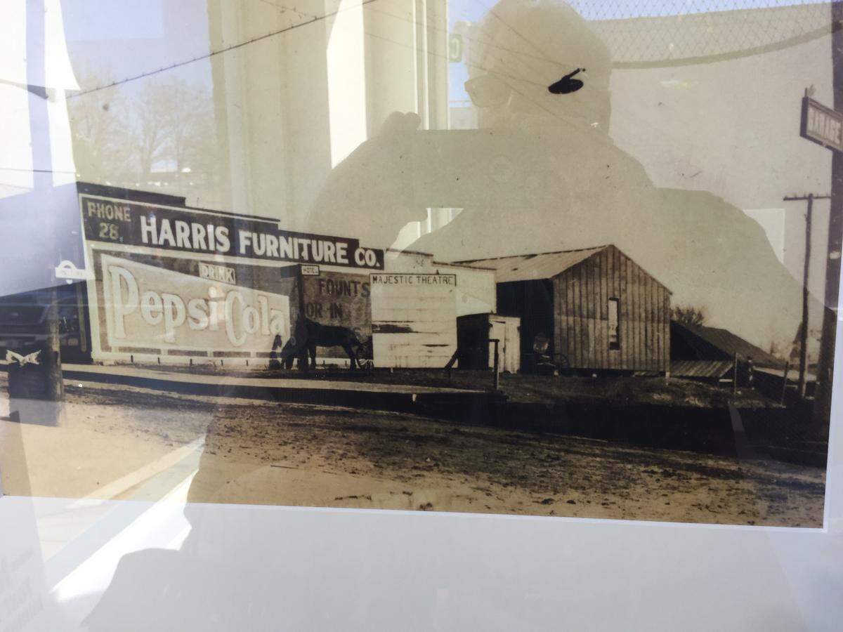 Hugh Bigham, the father of Improper Pig owner Will Bigham, grabs a shot of a picture showing the original building, including the sign on the outside wall, which was covered for decades after the building was expanded.