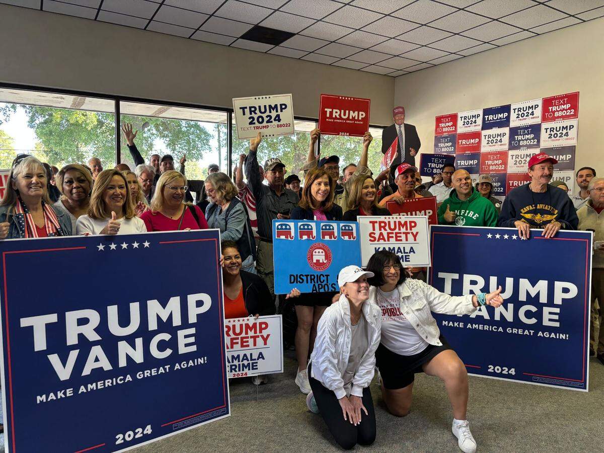 Cynthia Clementi and Lorena Castillo-Ritz pose in front of a group of Republican canvassers at the Mecklenburg GOP’s headquarters Saturday, Oct. 12, 2024.
