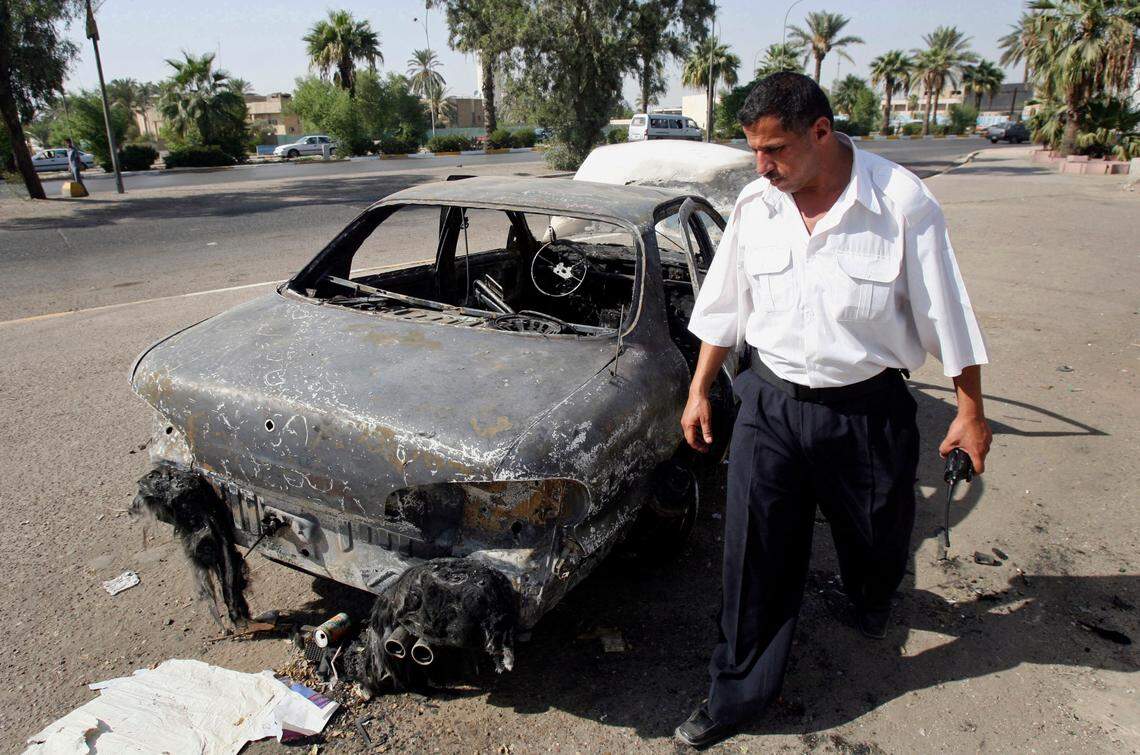 FILE - In this Sept. 25, 2007 file photo, an Iraqi traffic policeman inspects a car destroyed by a Blackwater security detail in al-Nisoor Square in Baghdad, Iraq. On Tuesday, Dec. 22, 2020, the Trump administration pardoned four military contractors convicted of killing 14 Iraqi civilians in a public square 13 years ago. (AP Photo/Khalid Mohammed, File)