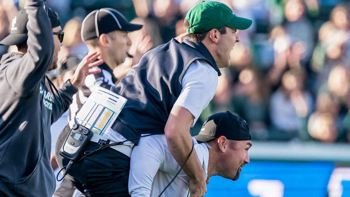 Charlotte Will Healy jumps on the back of director of football performance Chris Laskowski to celebrate a stop on fourth down against Middle Tennessee.