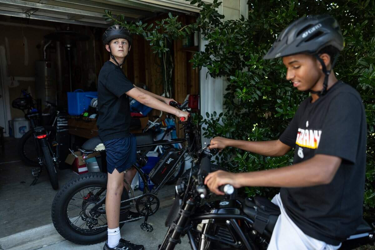 Cam Fuller, left, takes a break with his friend after riding their e-bikes around the neighborhood in Charlotte, N.C., on Monday, June 29, 2026.
