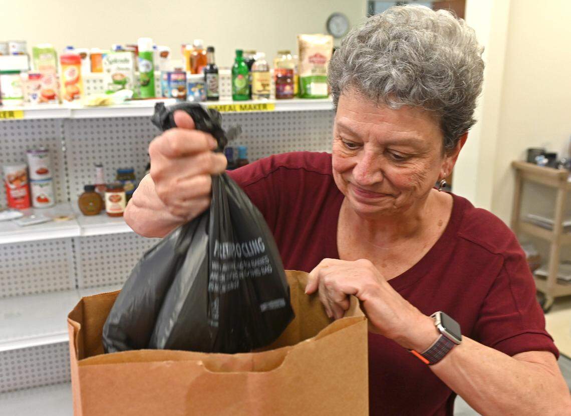 Loaves & Fishes volunteer Carol Moran fills a grocery sack with items for a client on Monday, February 27, 2023 at Holy Comforter Episcopal Church in Charlotte, NC. Loaves & Fishes/Friendship Trays have seen an explosion in need and are bracing for the end of increased snap benefits on Tuesday, February 28, 2023.