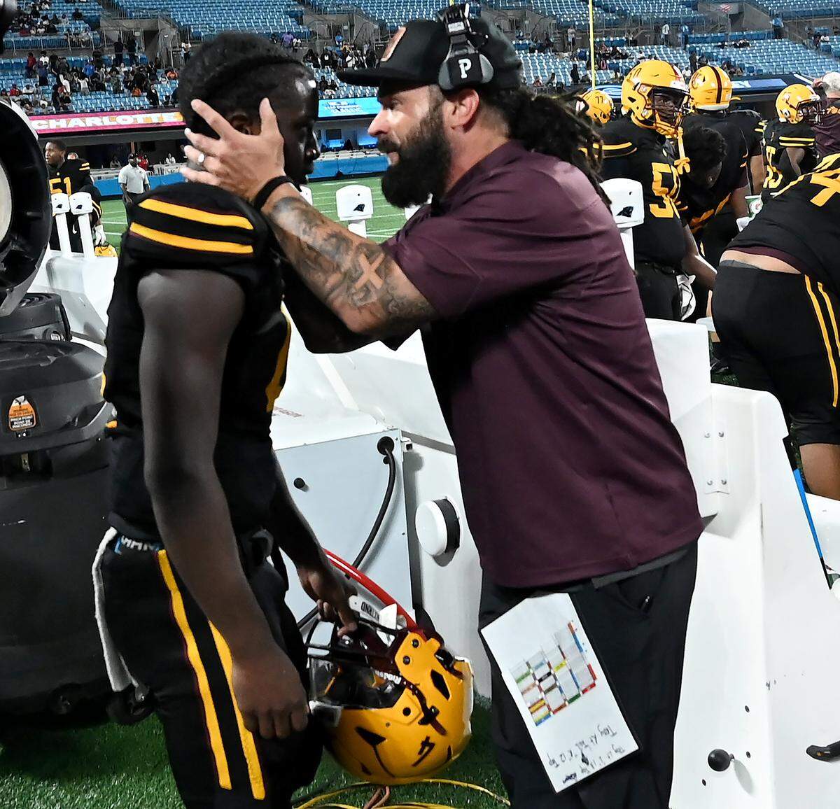 West Charlotte Lions head coach Sam Greiner, right, talks to quarterback Jamouri Nichols, left, following a touchdown run against the Grimsley Whirlies during overtime of the Keep Pounding Classic at Bank of America Stadium on Friday, August 22, 2025. Grimsley defeated West Charlotte 28-27. 