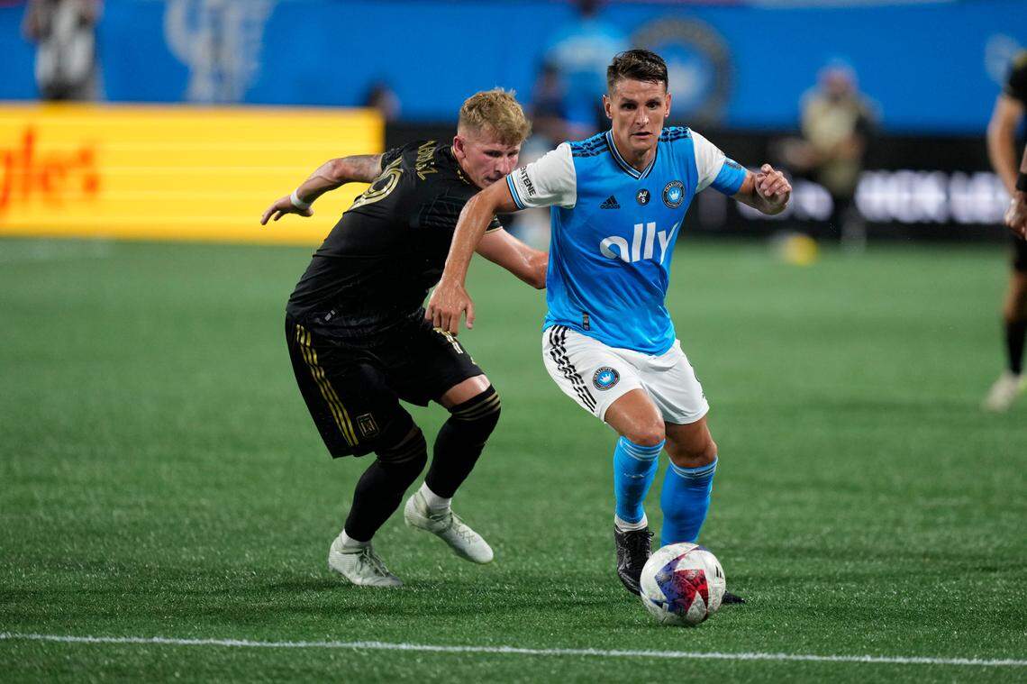 Charlotte FC midfielder Ashley Westwood (8) plays the ball pressured by Los Angeles FC midfielder Mateusz Bogusz (19) in the second half in the second half of an August match at Bank of America Stadium.