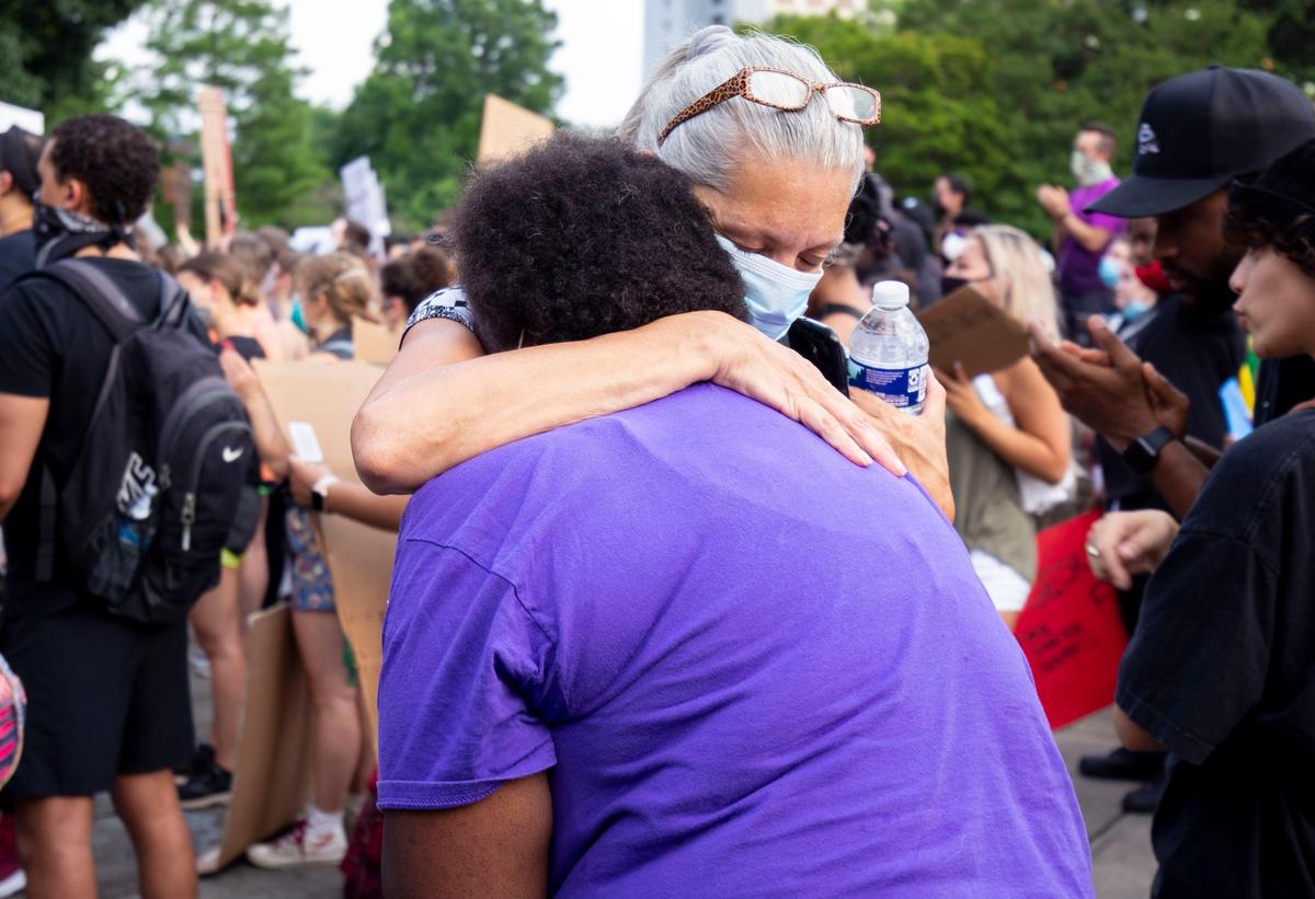 Protesters embrace after finishing a peaceful march around uptown at Marshall Park in Charlotte, NC on Monday, June 8, 2020.