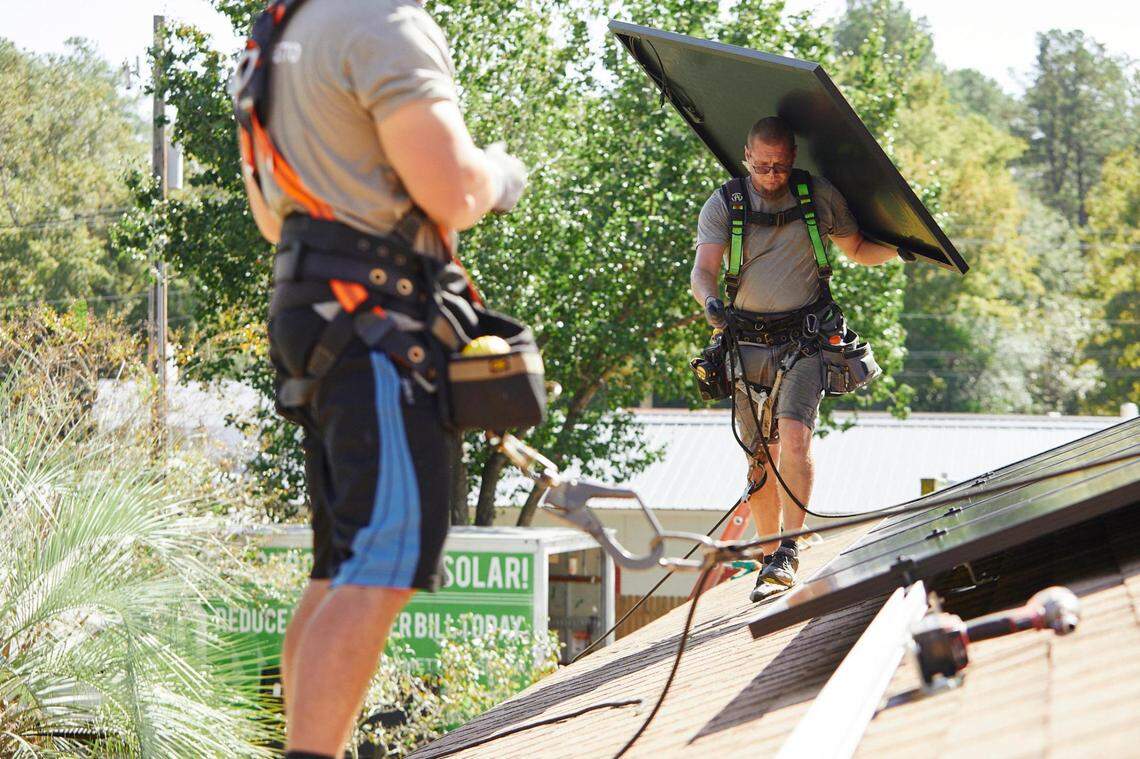Employees associated with Palmetto install solar panels. The company is moving to Charlotte.