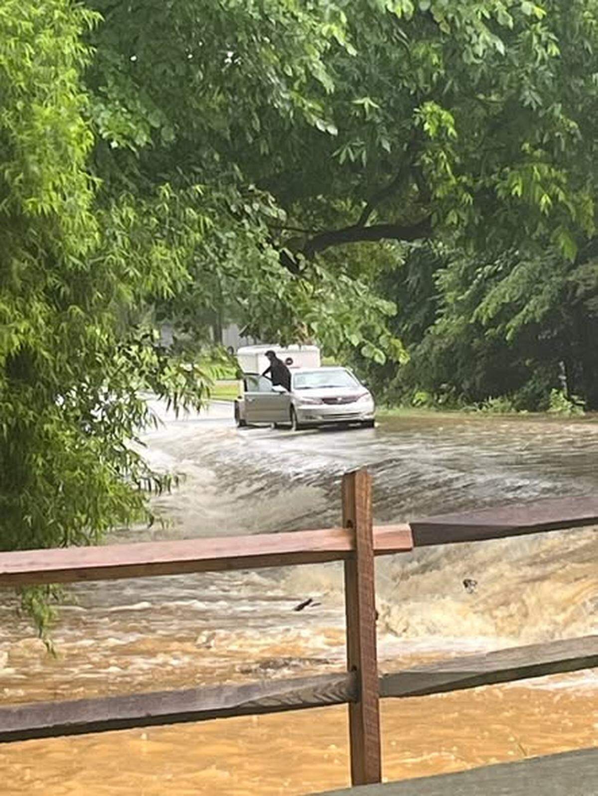 This photo released Saturday by the Union County Sheriff’s Office shows a person outside the open front passenger-side door of a car stopped on a flooded road.