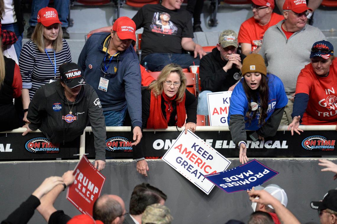 Supporters of President Donald J. Trump reach for placards being handed out prior to the start of a rally at Bojangles’ Arena in Charlotte, NC on Monday, March 2, 2020, on the eve of the Super Tuesday primaries.