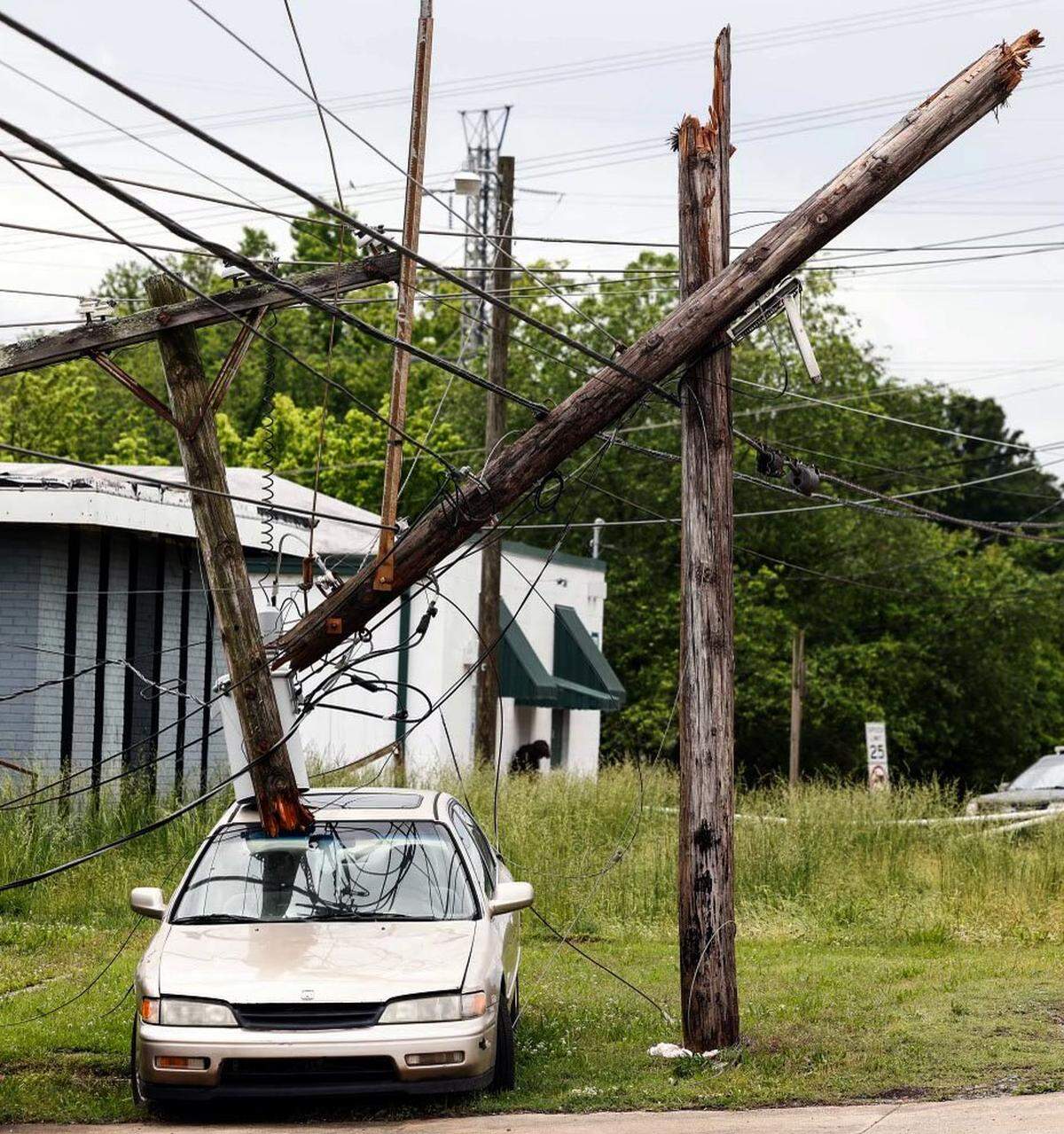 A broken utility pole rests on the top of a vehicle outside of McClure’s Auto Service on North Chester Street in Gastonia on Thursday, May 9, 2024. Severe storms tore through the area causing property damage and power outages.