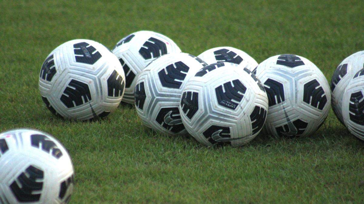 Soccer balls rest on a field.