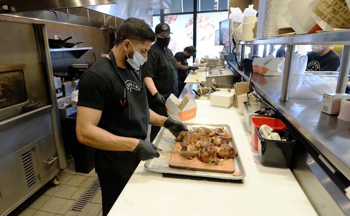 Angel Guazo cuts rotisserie chicken at Viva Chicken Waverly on May 14. The fast-casual Peruvian rotisserie chain is offering new hires a sign-on bonus of up to $400.