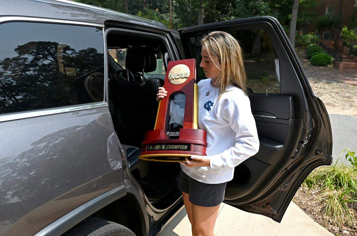 UNC field hockey coach Erin Matson carries the team’s 2022 national championship trophy to the team facility in Chapel Hill in June.