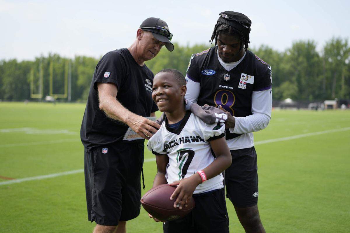 Jul 27, 2023; Owings Mills, MD, USA; Baltimore Ravens quarterback Lamar Jackson (8) signs a fan’s jersey while standing alongside Baltimore Ravens offensive coordinator Todd Monken after training camp practice at Under Armour Performance Center. Mandatory Credit: Brent Skeen-USA TODAY Sports